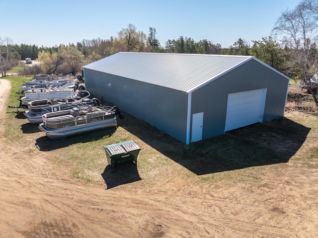 exterior space featuring driveway, metal roof, an outdoor structure, and a garage
