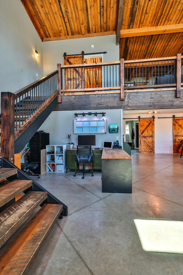 living room featuring a barn door, finished concrete floors, beamed ceiling, wood ceiling, and stairway