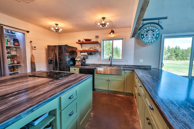 kitchen with green cabinetry, an inviting chandelier, a sink, wood counters, and black appliances