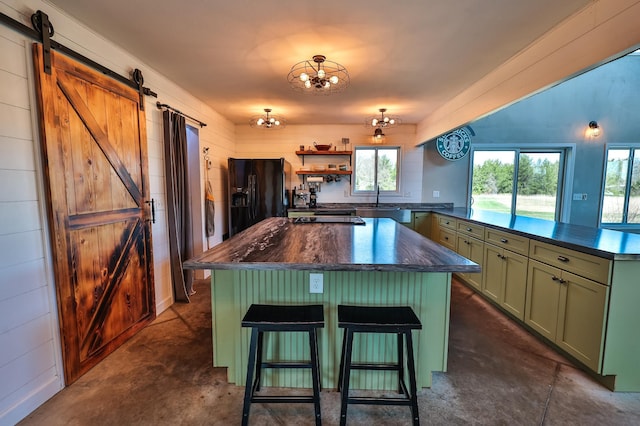 kitchen featuring green cabinetry, a barn door, black fridge, a peninsula, and a kitchen island
