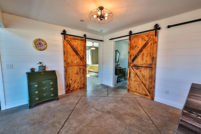 interior space featuring concrete flooring, wood walls, and a barn door