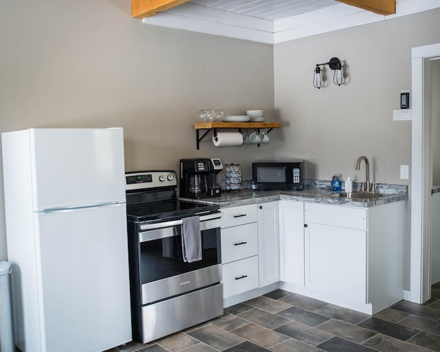 kitchen with electric range, black microwave, a sink, freestanding refrigerator, and white cabinetry