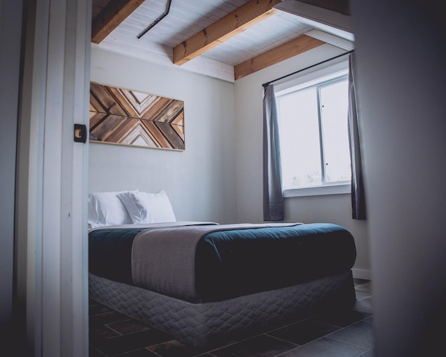 bedroom featuring beam ceiling and dark tile patterned flooring