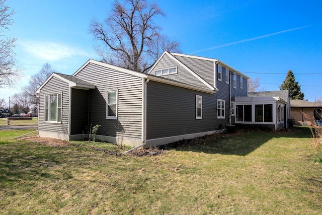 311 10th St S, Olivia, MN 56277 - view of side of home with a lawn, cooling unit, and a sunroom