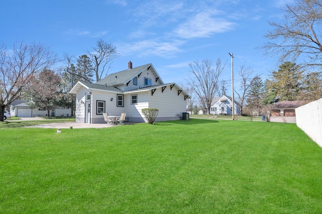 rear view of house featuring fence, roof with shingles, a chimney, a patio area, and a lawn