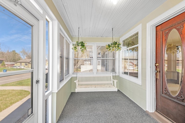 unfurnished sunroom featuring carpet floors and wood ceiling