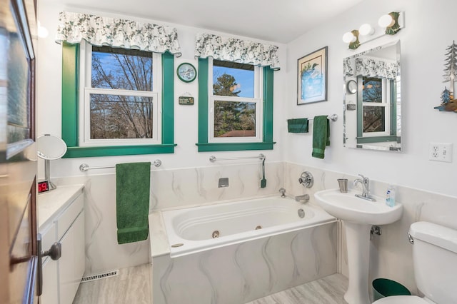 bathroom with a sink, a whirlpool tub, toilet, and visible vents