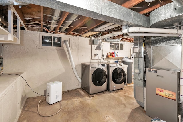 unfinished below grade area featuring heating unit and independent washer and dryer