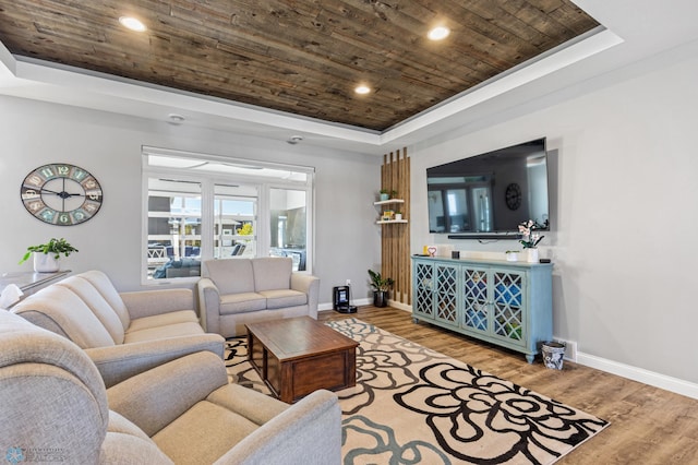 living room with a tray ceiling, baseboards, wood ceiling, and wood finished floors