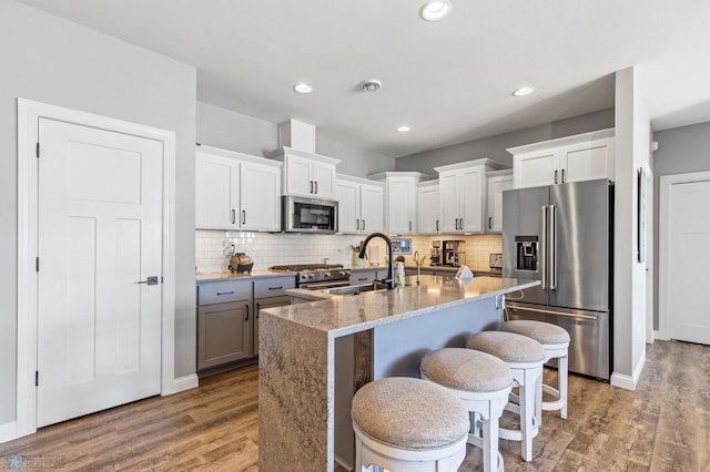 kitchen with a kitchen bar, wood finished floors, appliances with stainless steel finishes, and a sink