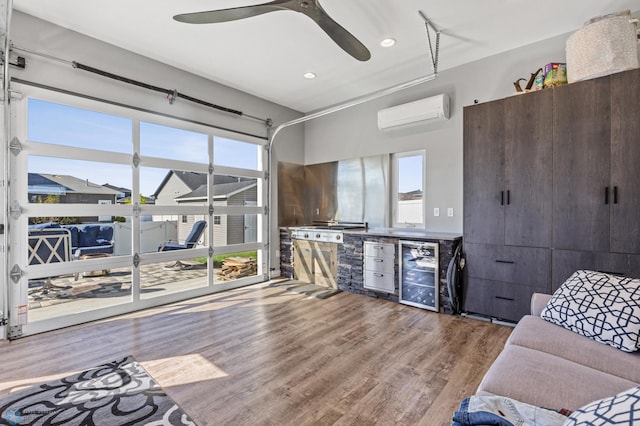 living area with an AC wall unit, a healthy amount of sunlight, beverage cooler, and wood finished floors