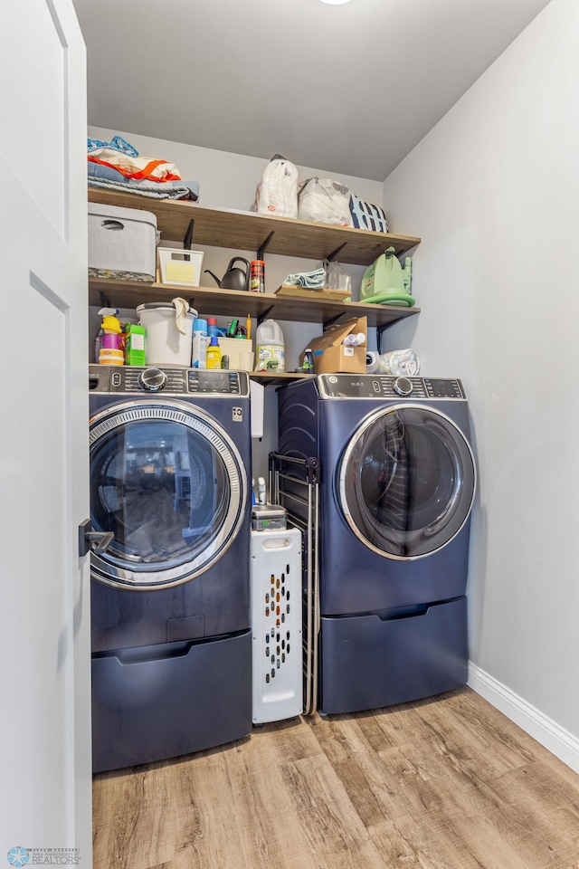 washroom with separate washer and dryer, baseboards, wood finished floors, and laundry area