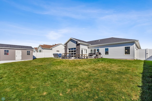 back of house with an outdoor structure, a yard, a patio area, and fence