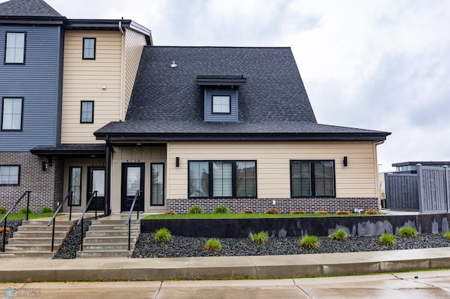 view of front of house with brick siding and roof with shingles
