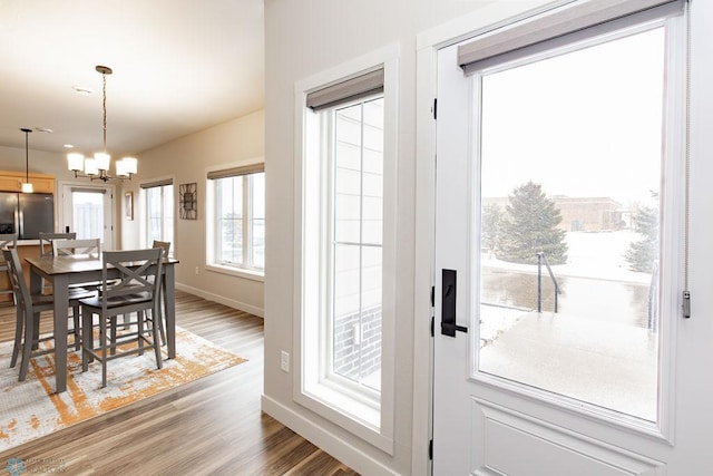 entryway with baseboards, an inviting chandelier, and light wood-style flooring