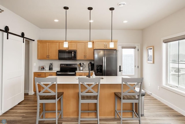kitchen featuring a barn door, stainless steel fridge, light wood finished floors, light countertops, and black range with electric stovetop