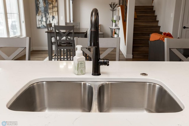room details with baseboards, a sink, wood finished floors, and light countertops