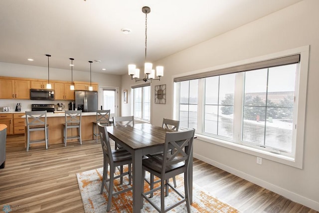 dining area featuring recessed lighting, light wood-style flooring, baseboards, and a notable chandelier