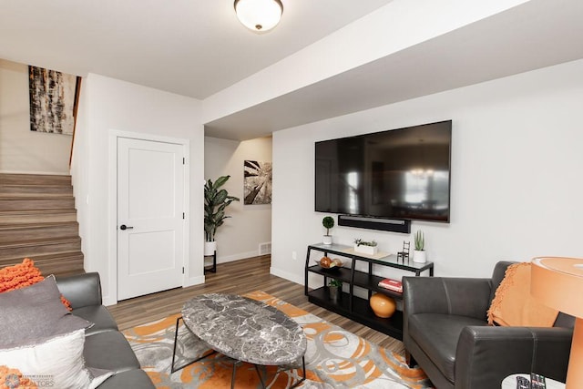 living area with stairway, baseboards, wood finished floors, and visible vents