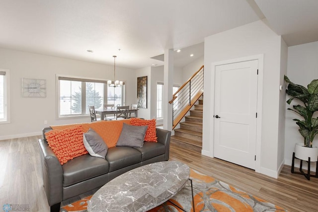 living room with stairs, baseboards, an inviting chandelier, and wood finished floors