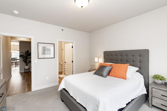 bedroom with baseboards, ensuite bathroom, and carpet