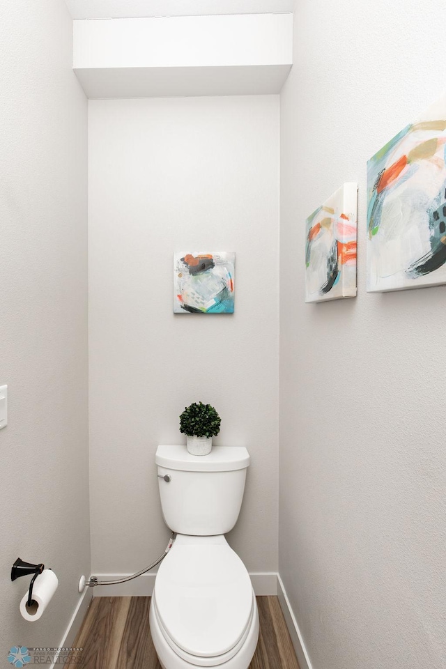 bathroom featuring baseboards, toilet, and wood finished floors