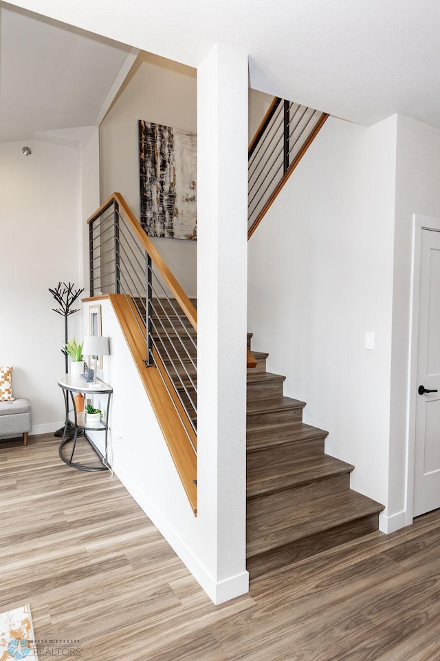staircase featuring baseboards and wood finished floors