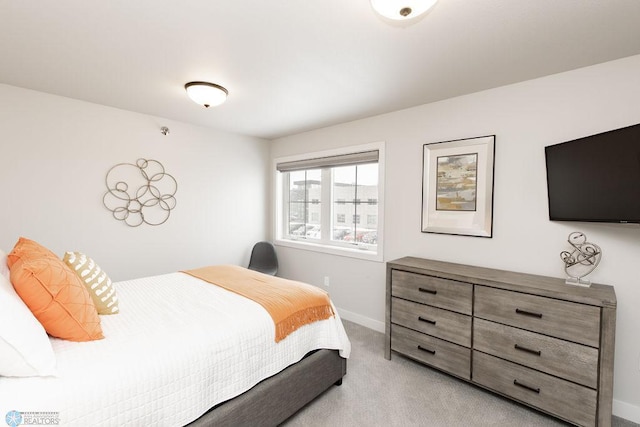 bedroom with light colored carpet and baseboards