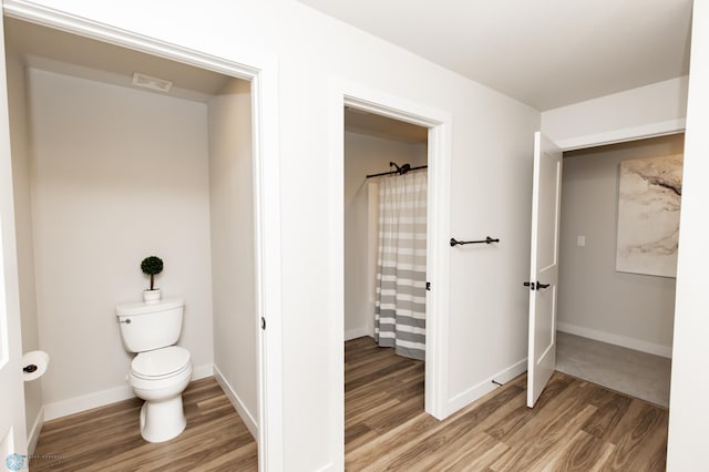 bathroom featuring visible vents, wood finished floors, baseboards, toilet, and a shower with shower curtain