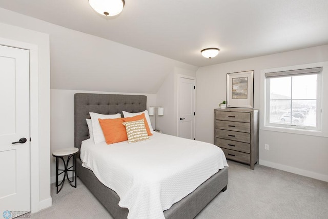 bedroom featuring baseboards, lofted ceiling, and light carpet