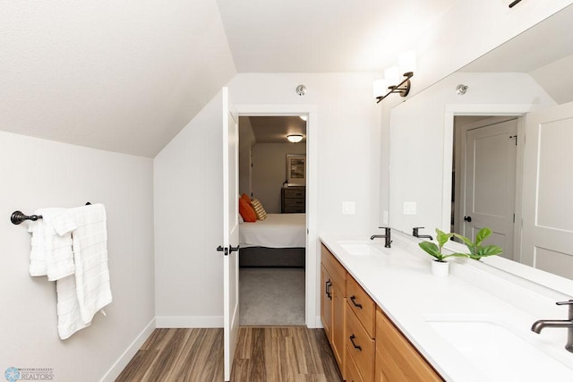 full bath featuring double vanity, a sink, wood finished floors, and vaulted ceiling