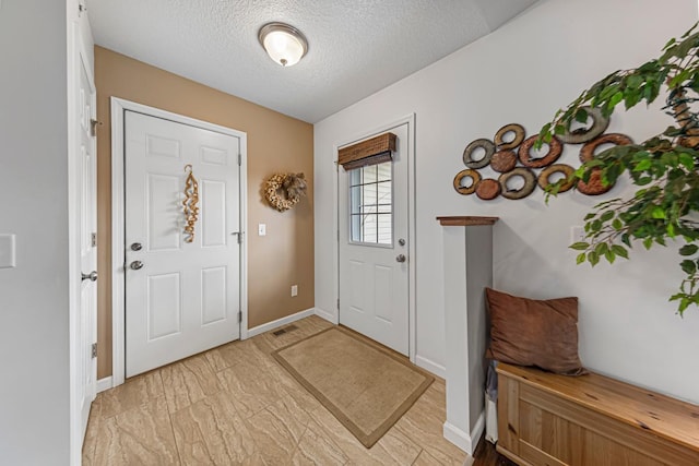 entryway featuring a textured ceiling and baseboards