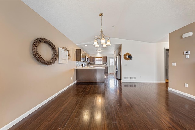 living room featuring vaulted ceiling, an inviting chandelier, visible vents, baseboards, and dark wood-style floors