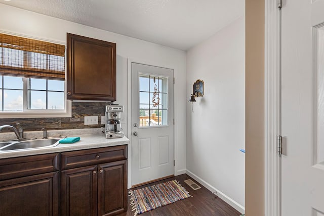 doorway featuring dark wood-type flooring, visible vents, baseboards, and a sink