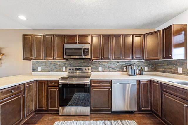 kitchen with backsplash, dark brown cabinetry, stainless steel appliances, and light countertops