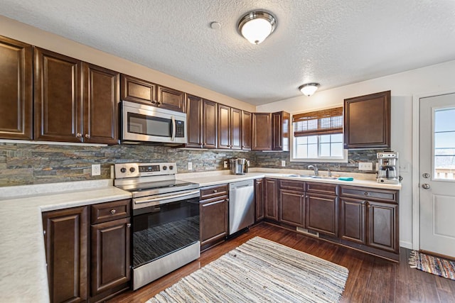 kitchen featuring light countertops, dark brown cabinets, appliances with stainless steel finishes, and a sink