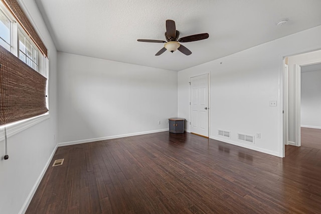 empty room featuring wood finished floors, baseboards, a ceiling fan, and visible vents