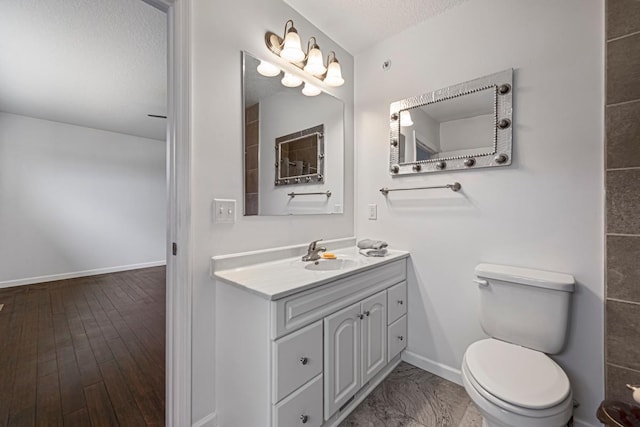 bathroom featuring a textured ceiling, toilet, baseboards, and vanity