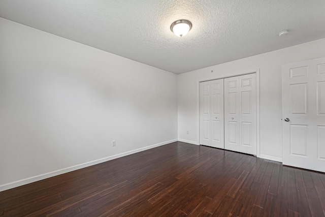 unfurnished bedroom with baseboards, a textured ceiling, dark wood-type flooring, and a closet