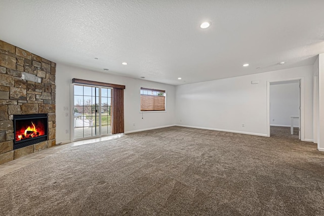 unfurnished living room with recessed lighting, carpet, baseboards, a fireplace, and a textured ceiling