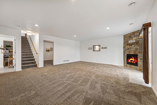 unfurnished living room with carpet flooring, baseboards, recessed lighting, stairway, and a stone fireplace