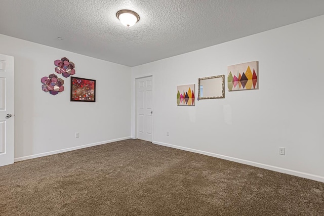 empty room featuring dark carpet, baseboards, and a textured ceiling