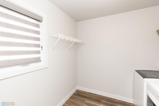 laundry area with laundry area, washer and clothes dryer, baseboards, and wood finished floors