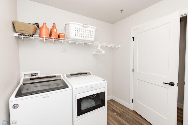 clothes washing area with laundry area, baseboards, wood finished floors, and washer and dryer