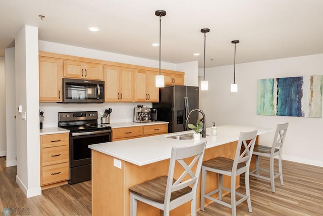 kitchen featuring black / electric stove, a breakfast bar area, stainless steel fridge, light brown cabinets, and light wood-style flooring