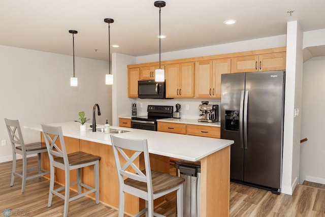 kitchen with a sink, light brown cabinetry, black appliances, and light wood-style flooring