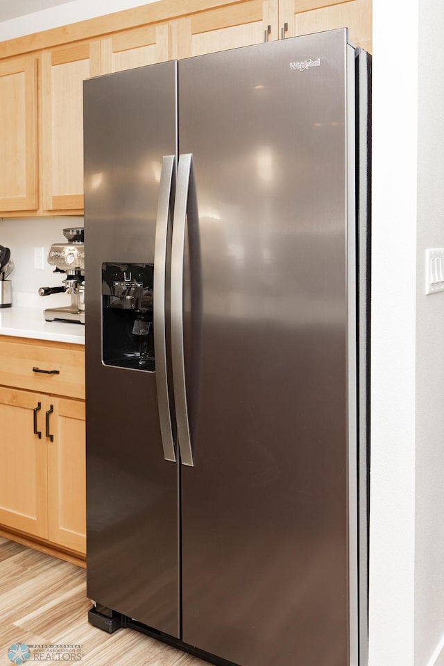 interior details with stainless steel fridge, light brown cabinetry, light wood-style floors, and light countertops
