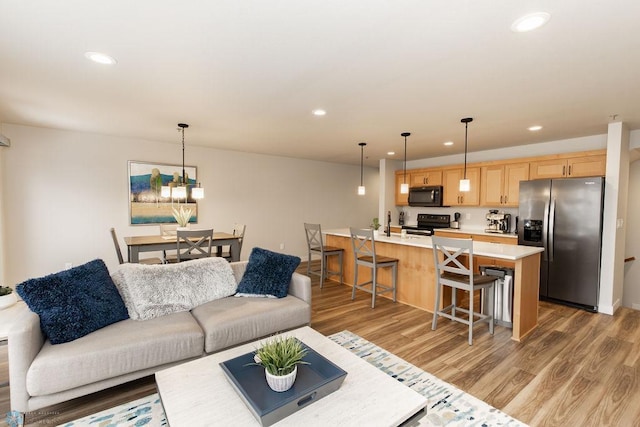 living area with light wood-type flooring and recessed lighting