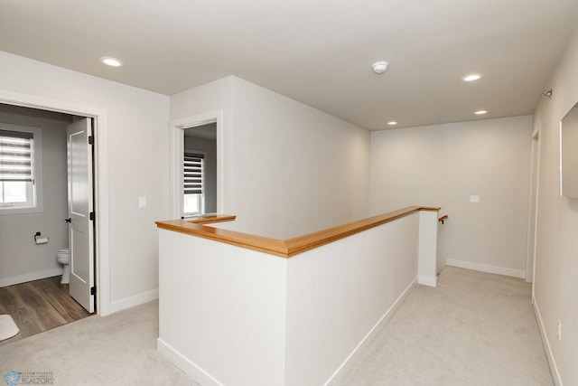 hallway featuring recessed lighting, baseboards, light colored carpet, and an upstairs landing