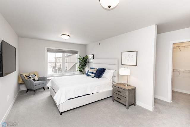 bedroom featuring baseboards, a spacious closet, light carpet, and a closet